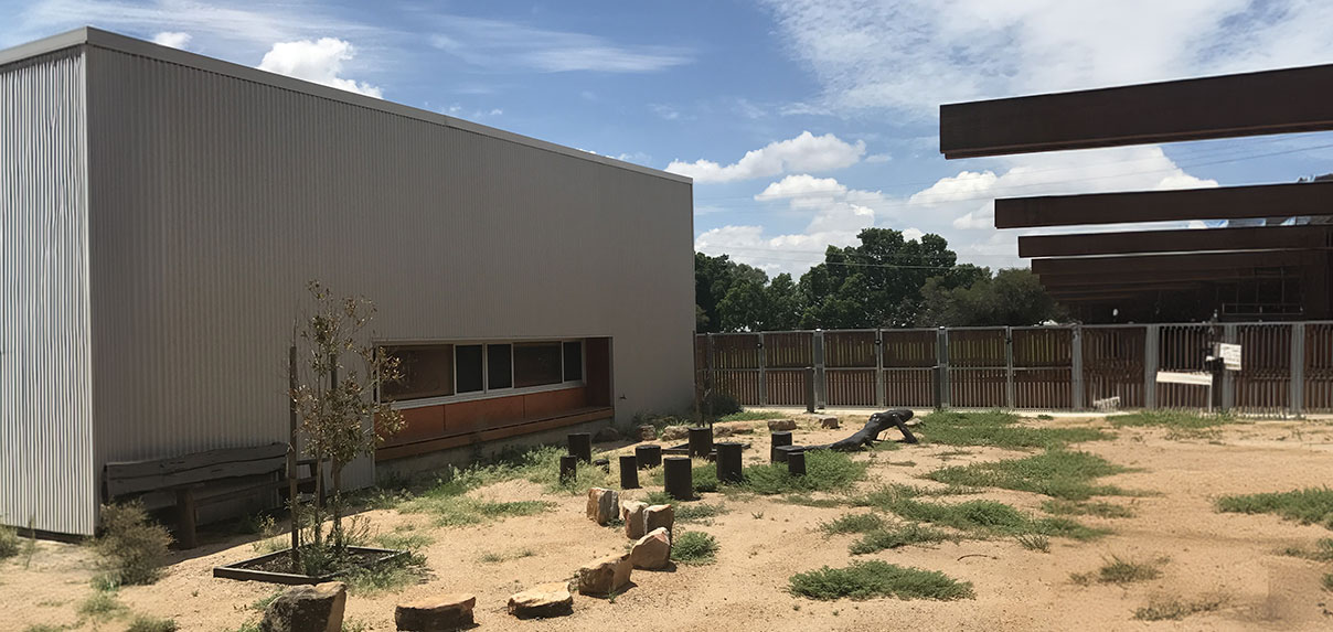 Outdoor community space featuring a natural landscape with rustic seating for gatherings and activities.