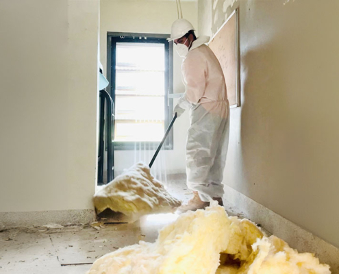 Worker safely removing insulation materials in a protective suit.