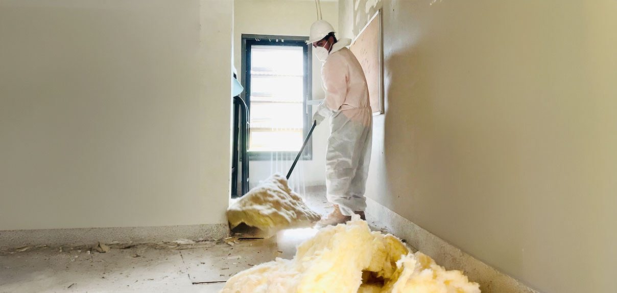 Worker safely removing insulation materials in a protective suit.
