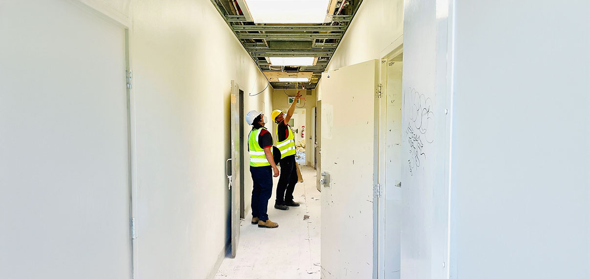 Workers inspecting ceiling wiring during building maintenance.